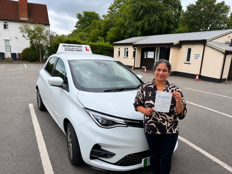 Woman holding driving test certificate standing next to white car at test centre
